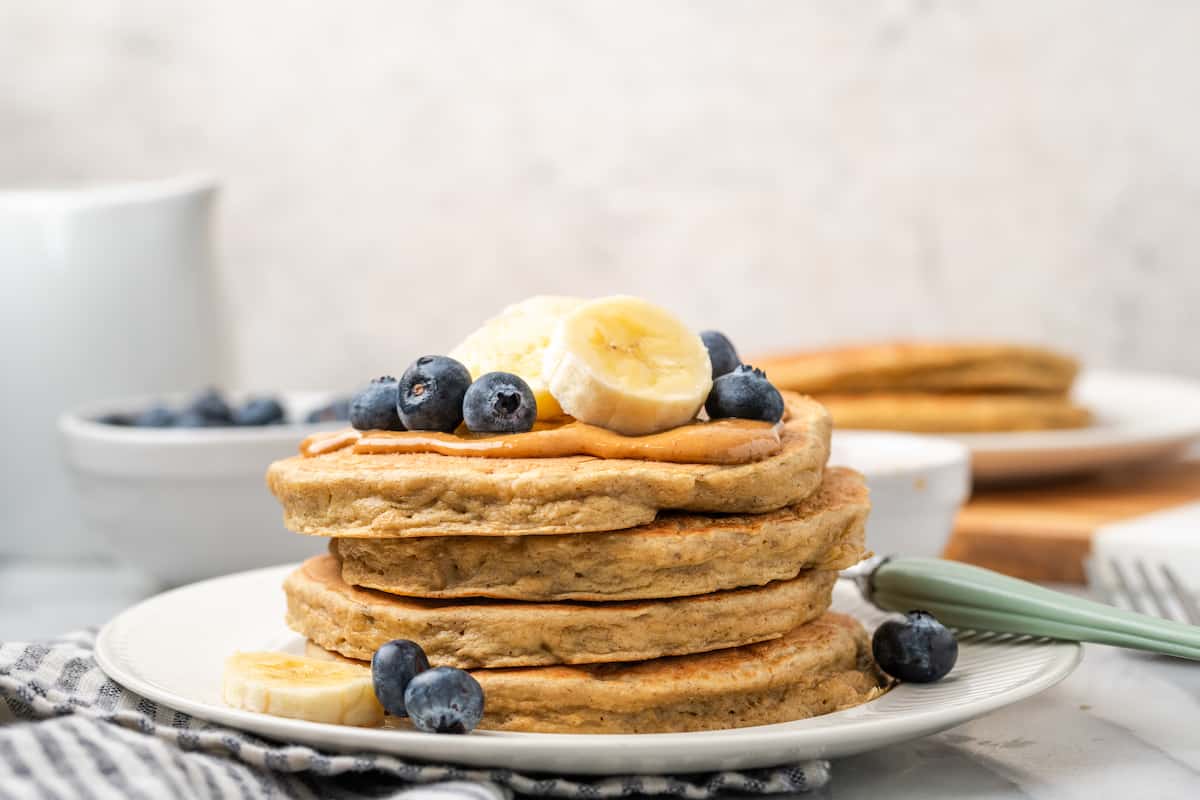 A stack of gluten-free protein pancakes topped with blueberries and sliced bananas.