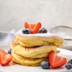 A stack of gluten-free souffle pancakes on a plate with fruit.