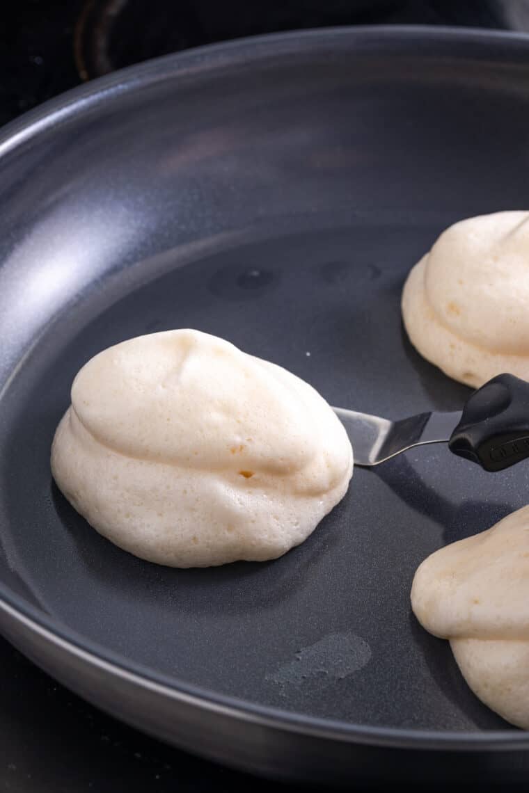 Cooking gluten-free souffle pancakes in a pan.