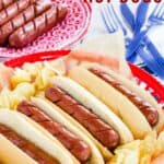Four hot dogs in buns in a basket with potato chips and four more cooked hot dogs in a plate behind them with text overlay that says "Air Fryer Hot Dogs".