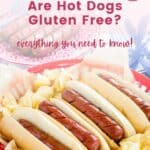 Four hot dogs in buns in a red basket with potato chips with text overlay that says "Are Hot Dogs Gluten Free? - Everything You Need to Know!".