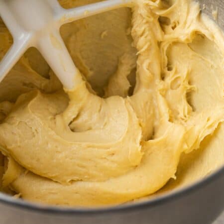 Choux pastry dough in the bowl of a mixer with a paddle attachment.