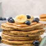 A stack of pancakes on a plate topped with peanut butter, blueberries, and banana slices with text overlay that says "Gluten Free Protein Pancakes".