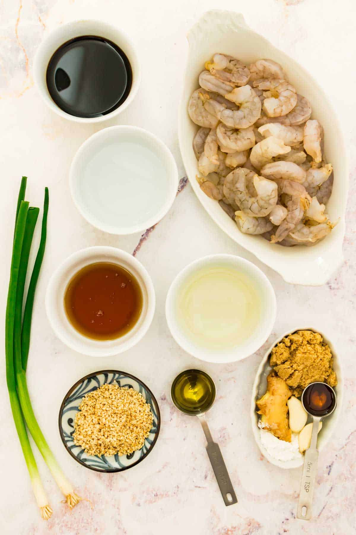 Ingredients for teriyaki shrimp are shown on a white background including shrimp, oil, fresh ginger, soy sauce, green garlic, and garlic.