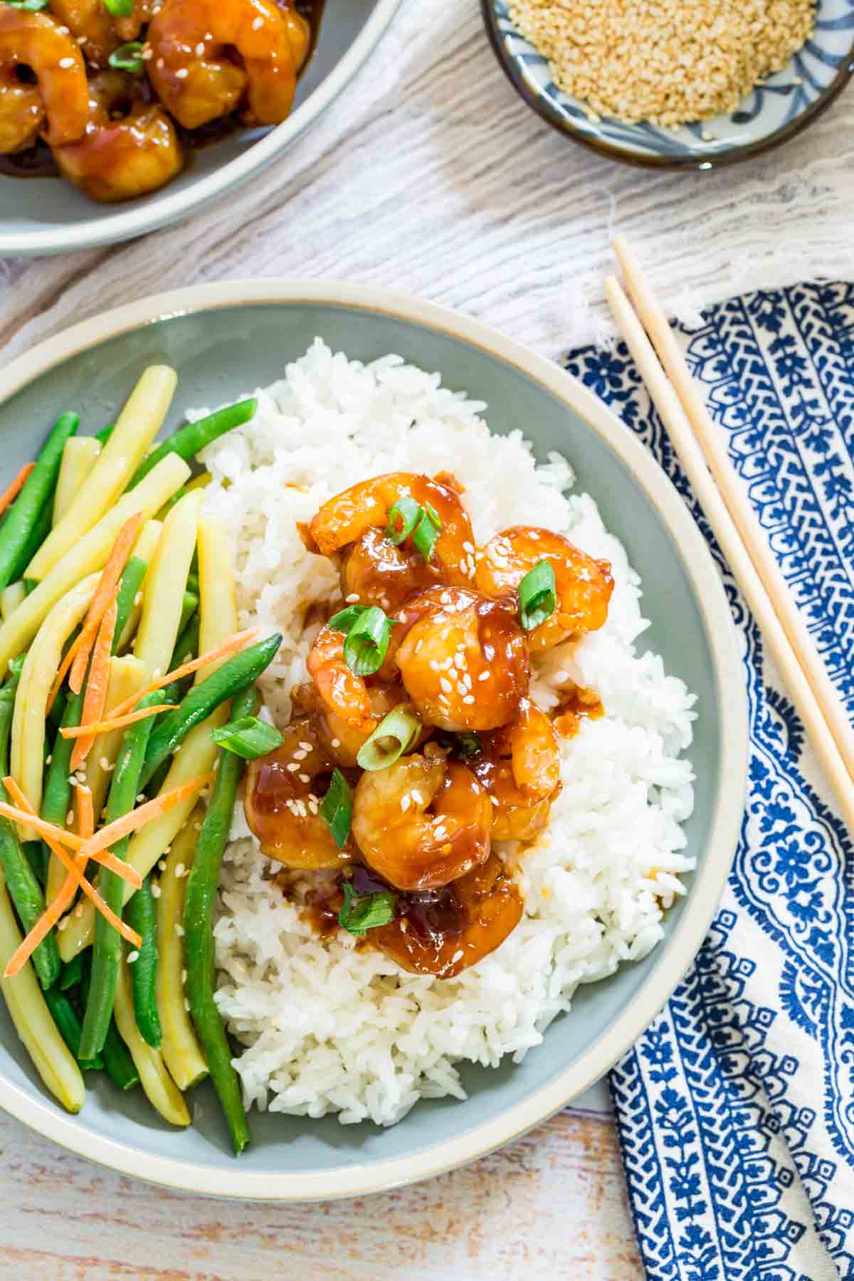 Teriyaki shrimp is shown on a bed of white rice on a plate.