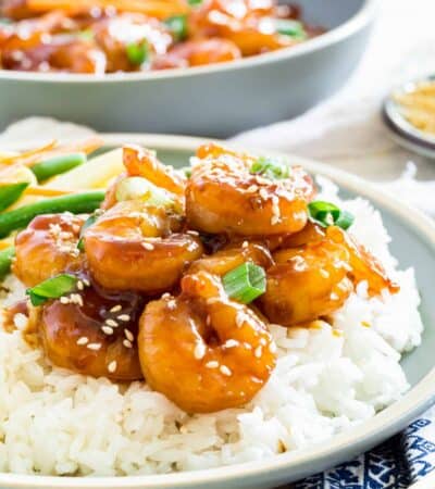 Teriyaki shrimp is shown on a bed of white rice on a plate.