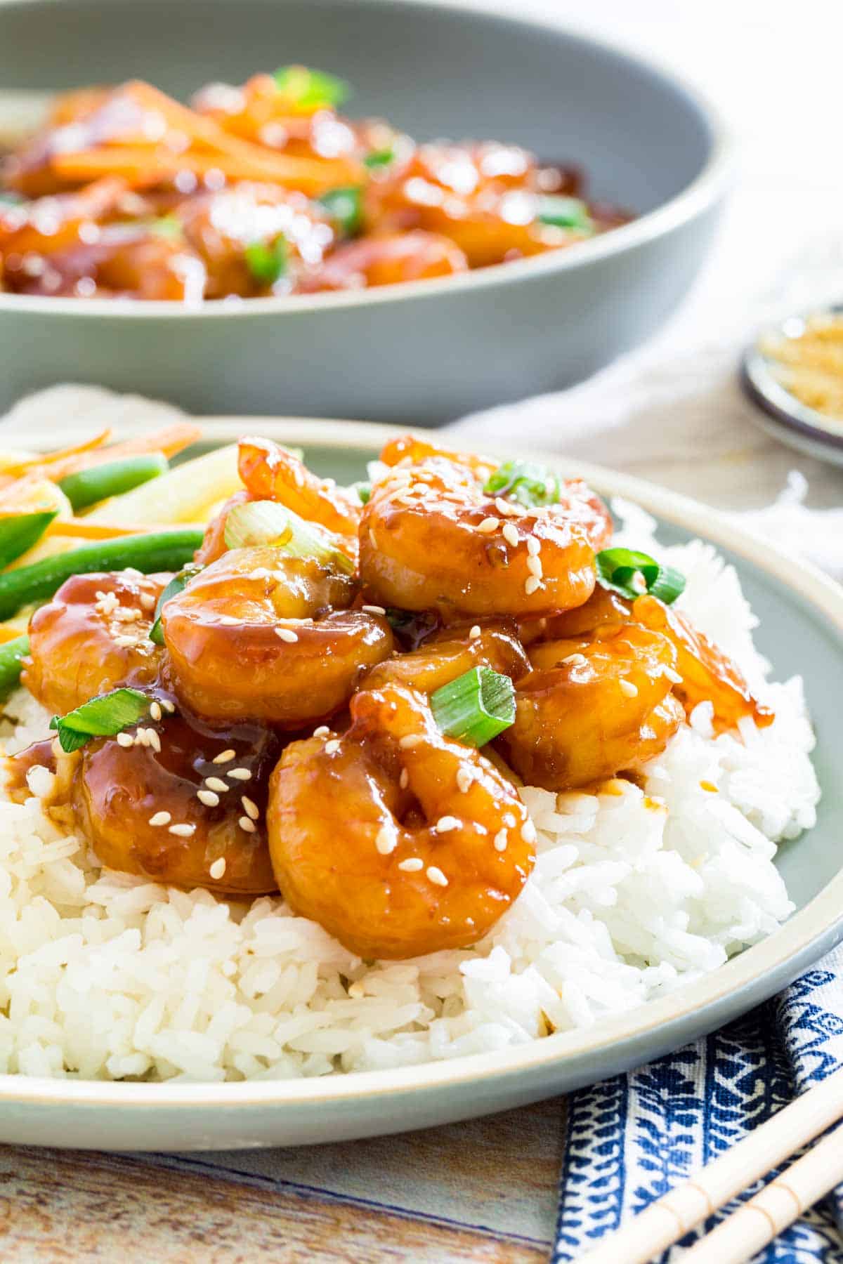 Teriyaki shrimp is shown on a bed of white rice on a plate.