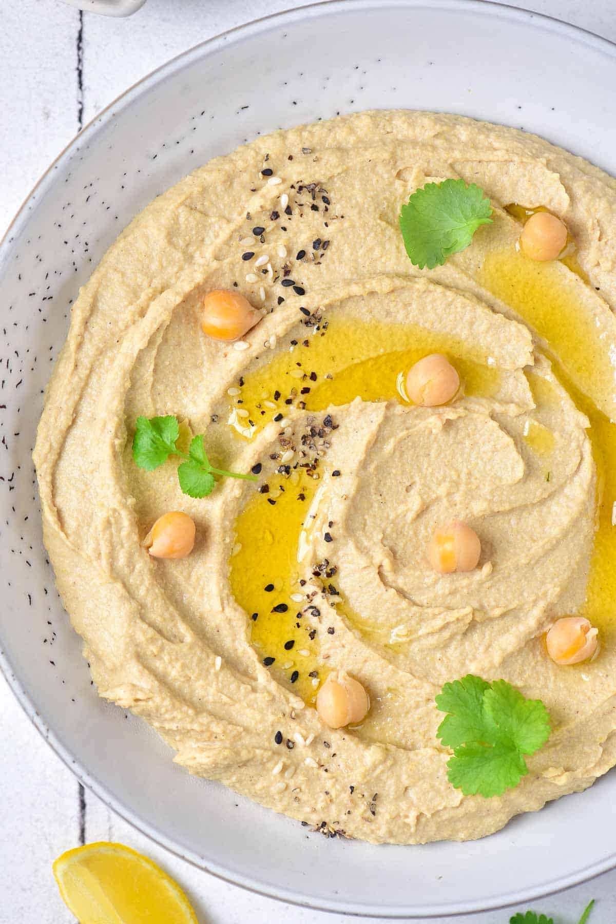 A bowl of hummus topped with olive oil and cilantro.