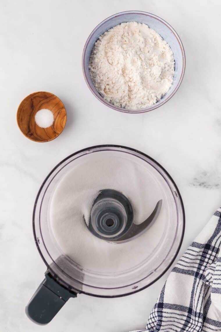Sugar is shown in a food processor along with salt and gluten-free flour.