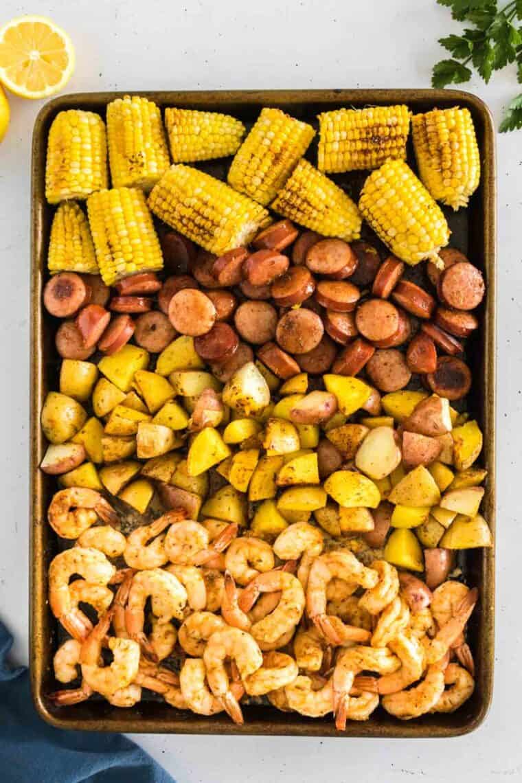 Shrimp, potatoes, sausage, and corn on the cob are cooked together on a sheet pan.