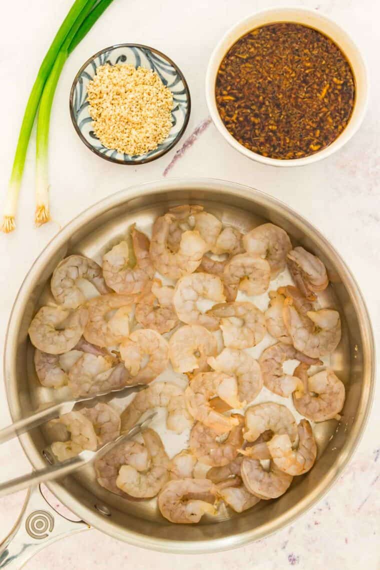Raw shrimp is added to a pan.