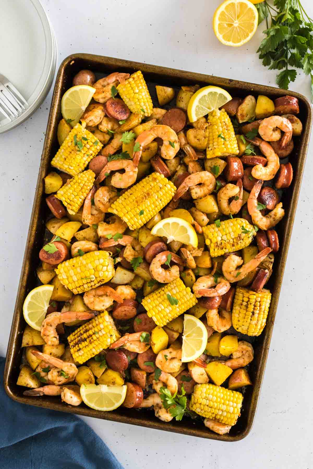 A sheet pan shrimp boil with shrimp, corn, potatoes, and sausage on a baking sheet.