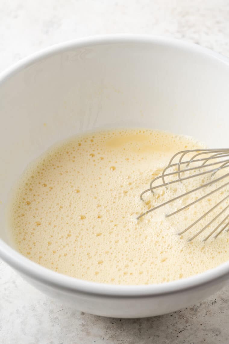 Whisking eggs in a white bowl.