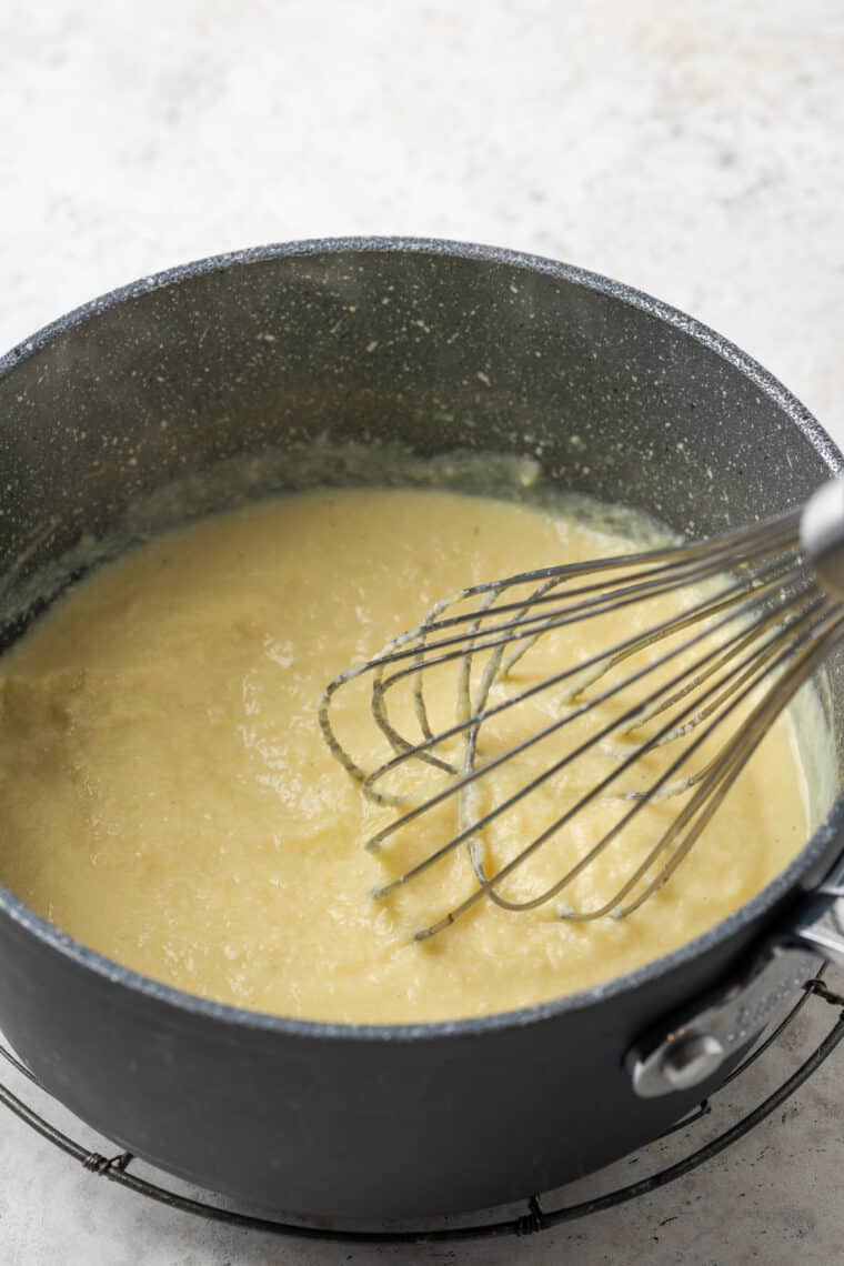 Pastry cream is whisked in a metal bowl.