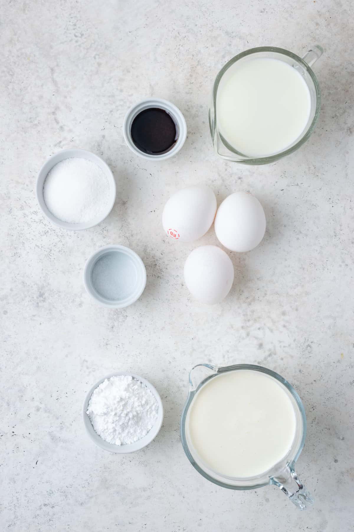 Ingredients needed to make Gluten-Free Bismark Donuts, including eggs, vanilla, and more, are shown in an overhead shot.