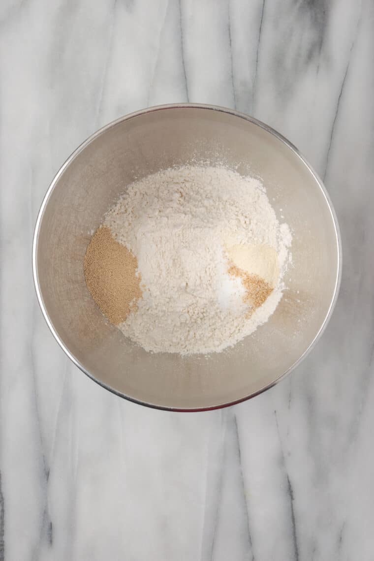 Yeast, flour, and salt are placed in a metal bowl.