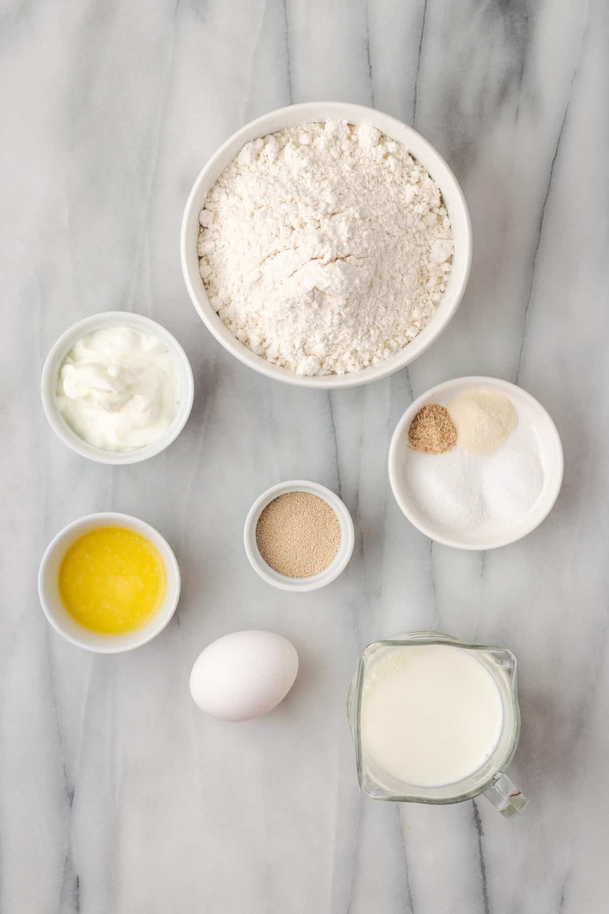 Ingredients needed to make gluten-free naan bread including gluten-free flour, an egg, butter, salt, and milk.
