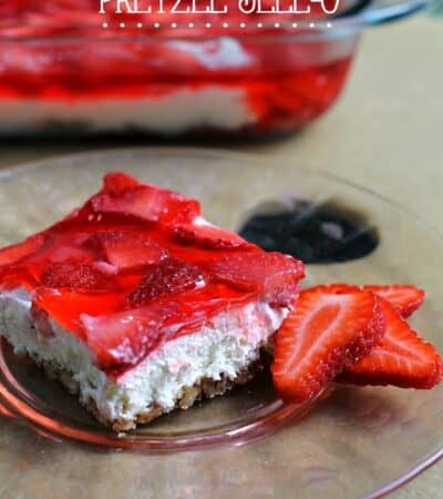 A square piece of strawberry pretzel jello dessert on a glass plate.