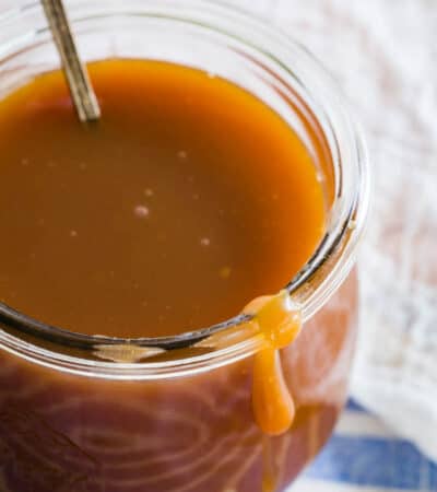 Caramel sauce in a glass jar with a spoon.