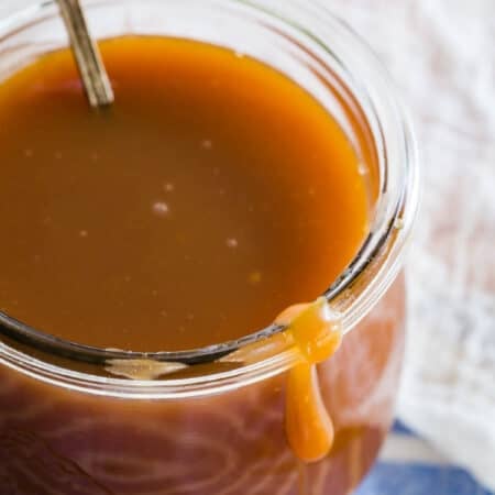 Caramel sauce in a glass jar with a spoon.