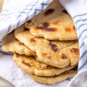 Several naan breads wrapped in a blue and white towel.