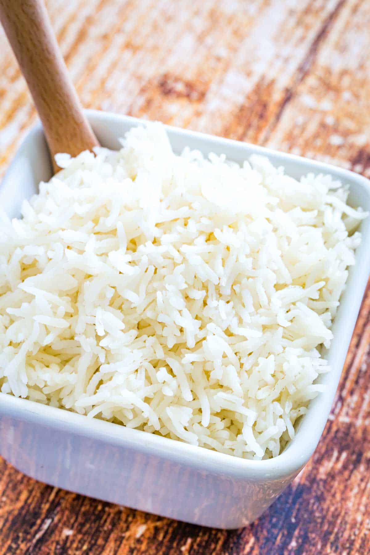 Basmati rice in a white bowl on a wooden countertop.