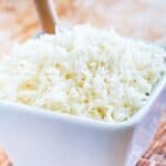 Basmati rice in a white bowl on a wooden countertop.