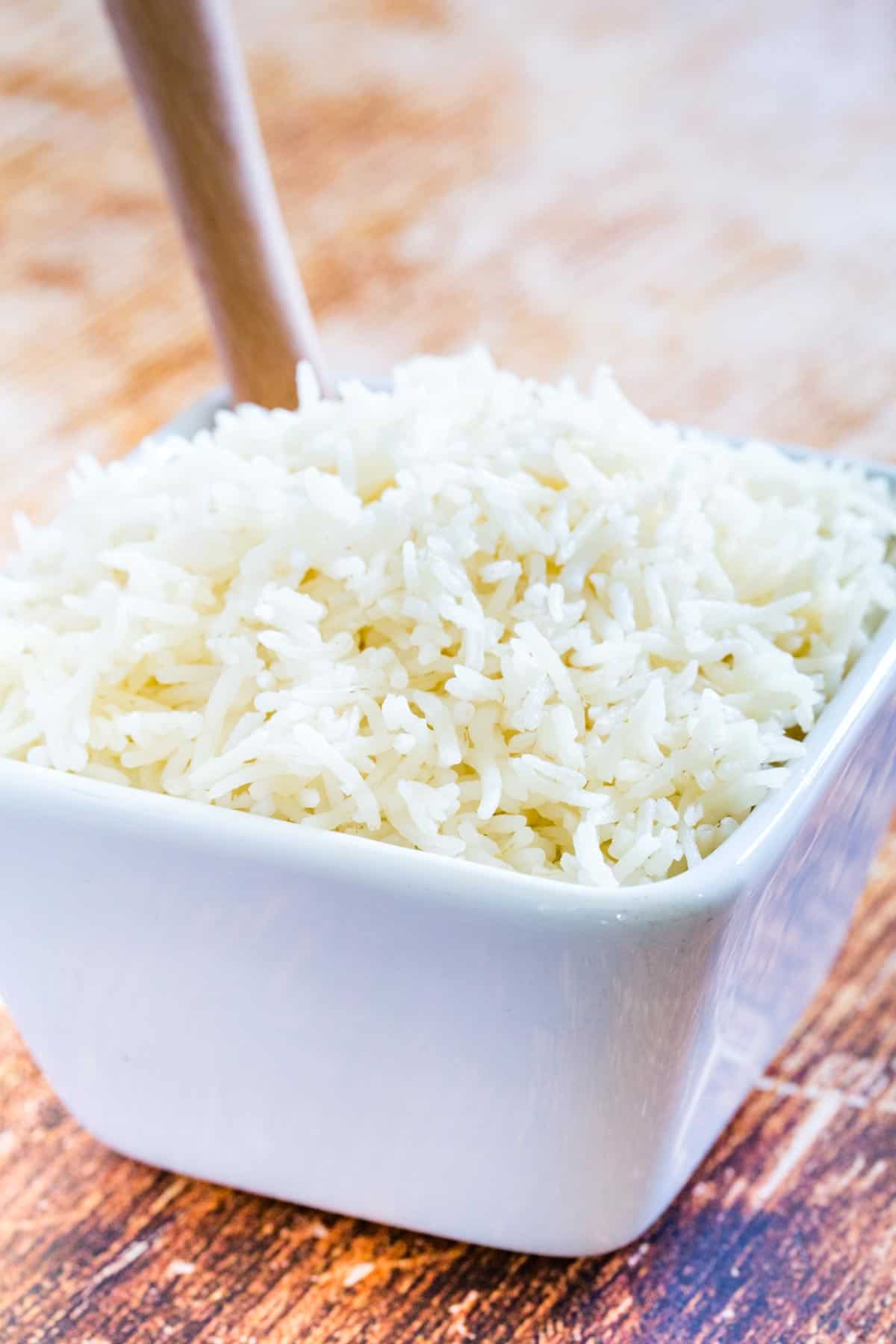 Basmati rice in a white bowl on a wooden countertop.