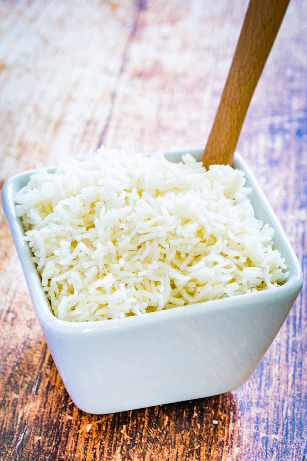 Basmati rice in a white bowl on a wooden countertop.