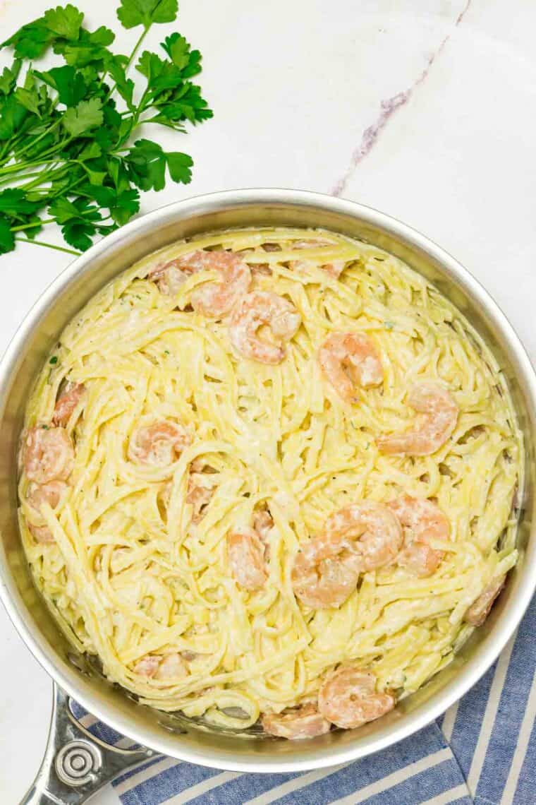 Mixing shrimp into pasta in a bowl.