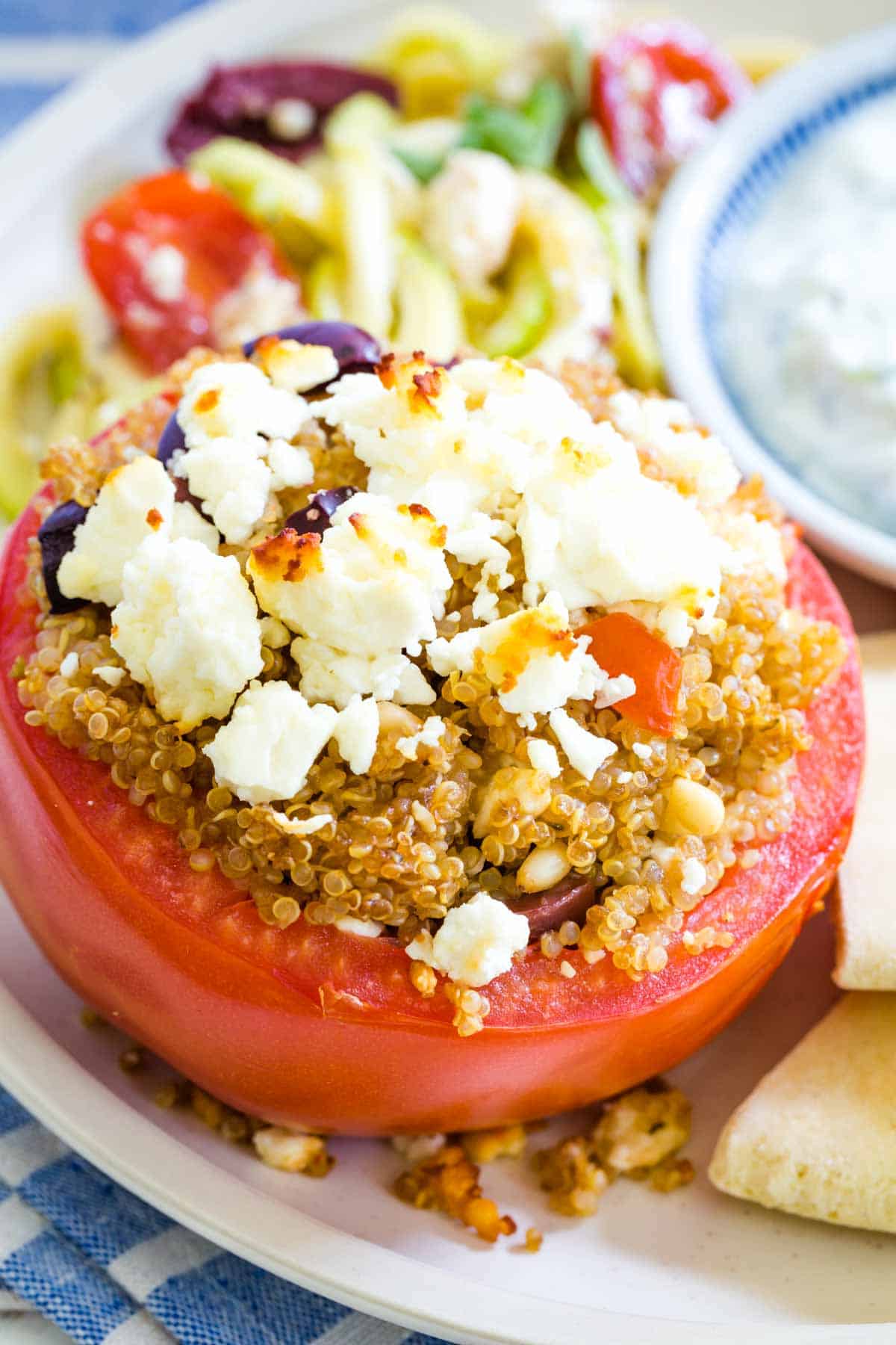 Close up of a quinoa stuffed tomato topped with feta cheese.