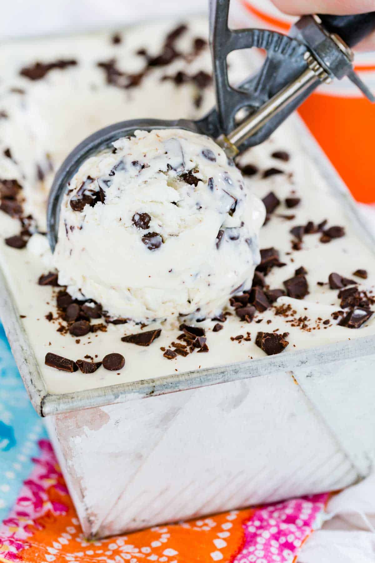 An ice cream scoop scoops out chocolate chip ice cream.