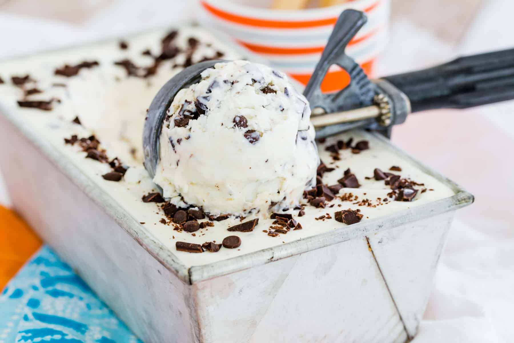 An ice cream scoop scoops out chocolate chip ice cream.