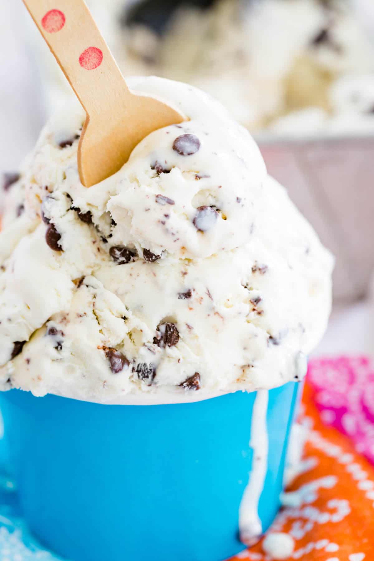 A close up shot of no churn chocolate chip ice cream in a blue cup with a spoon.