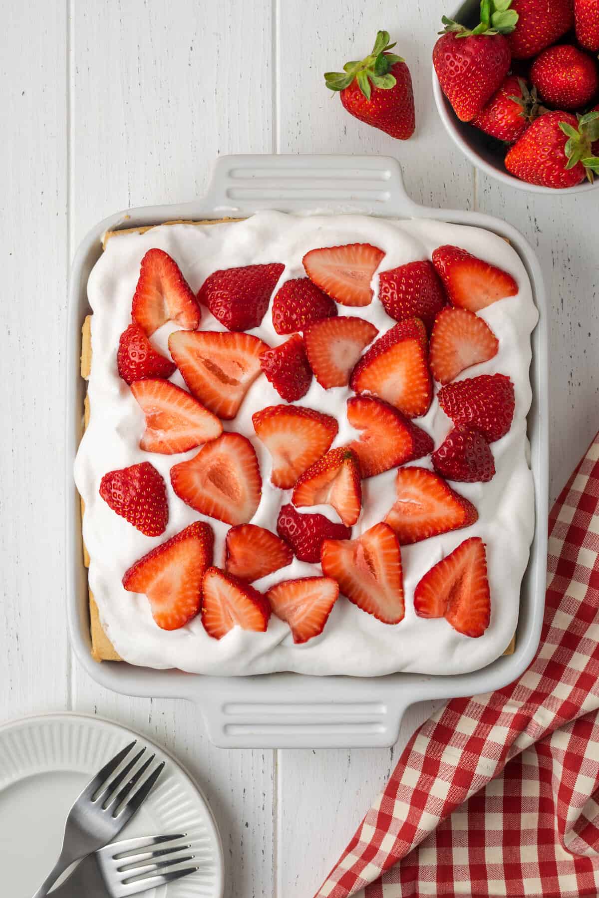An overhead view of a pan of gluten-free strawberry icebox cake topped with strawberries.