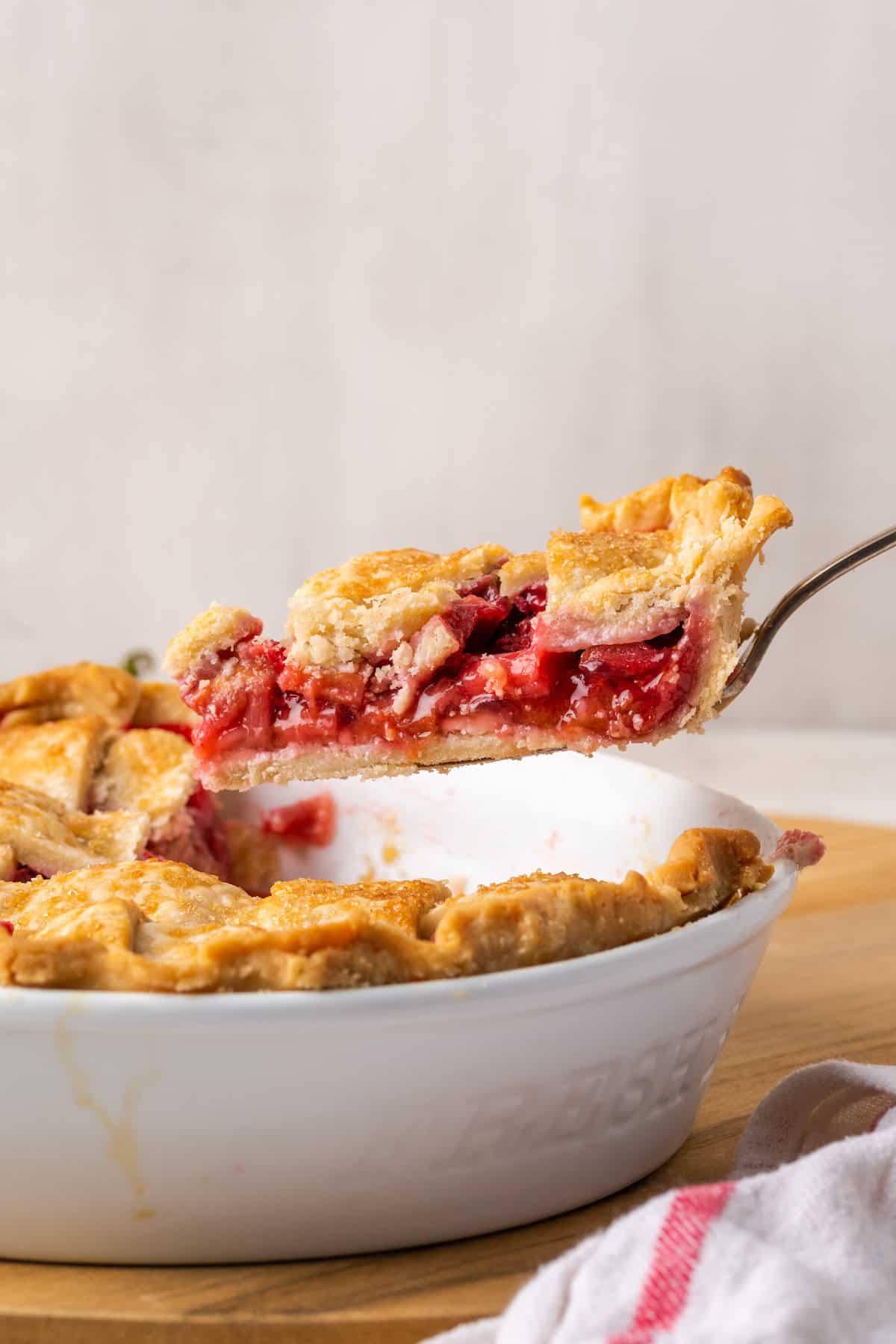 A pie server lifts out a slice of strawberry rhubarb pie.