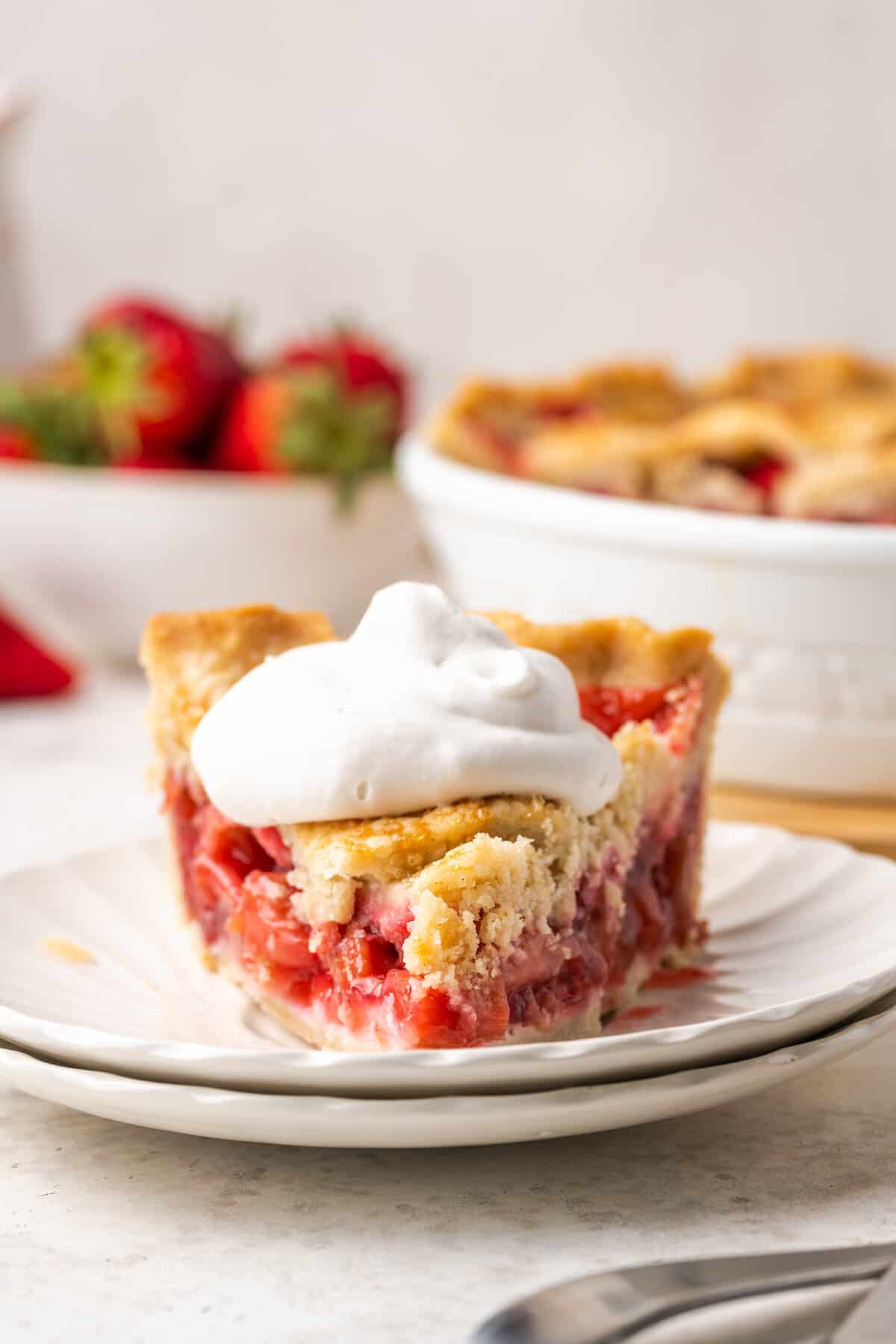 A slice of g-f strawberry rhubarb pie topped with whipped cream.