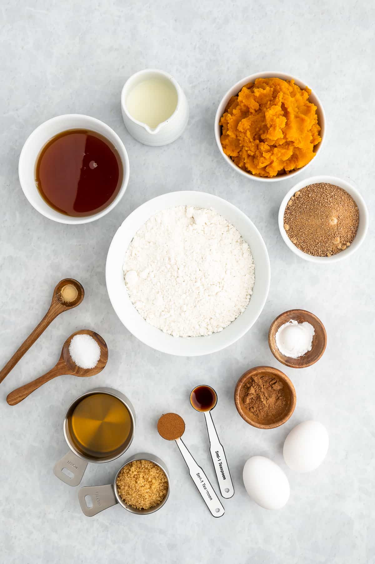 Ingredients for gluten-free pumpkin muffins: gluten-free flour, salt, vanilla, eggs, pumpkin puree, milk, maple syrup, coconut sugar.