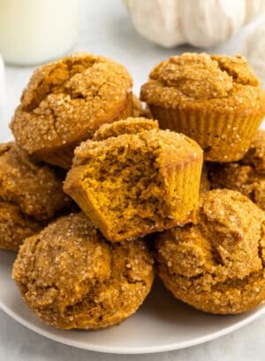 A plate of gluten-free pumpkin muffins with a bite taken out of one.