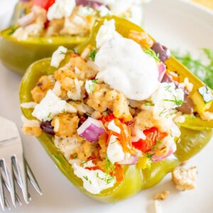 A closeup of a Greek chicken stuffed green pepper with a dollop of tzatziki on top.