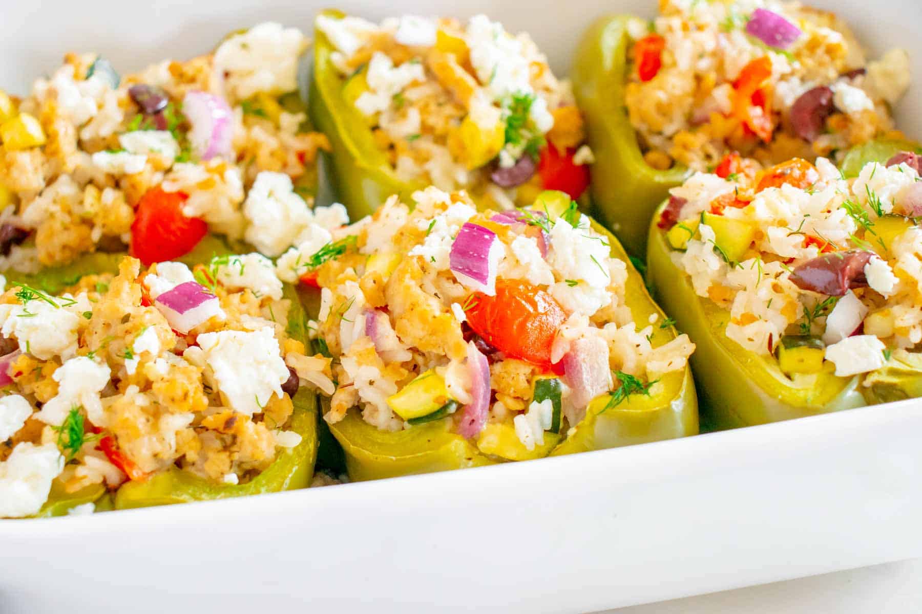 A white baking dish of chicken stuffed peppers.