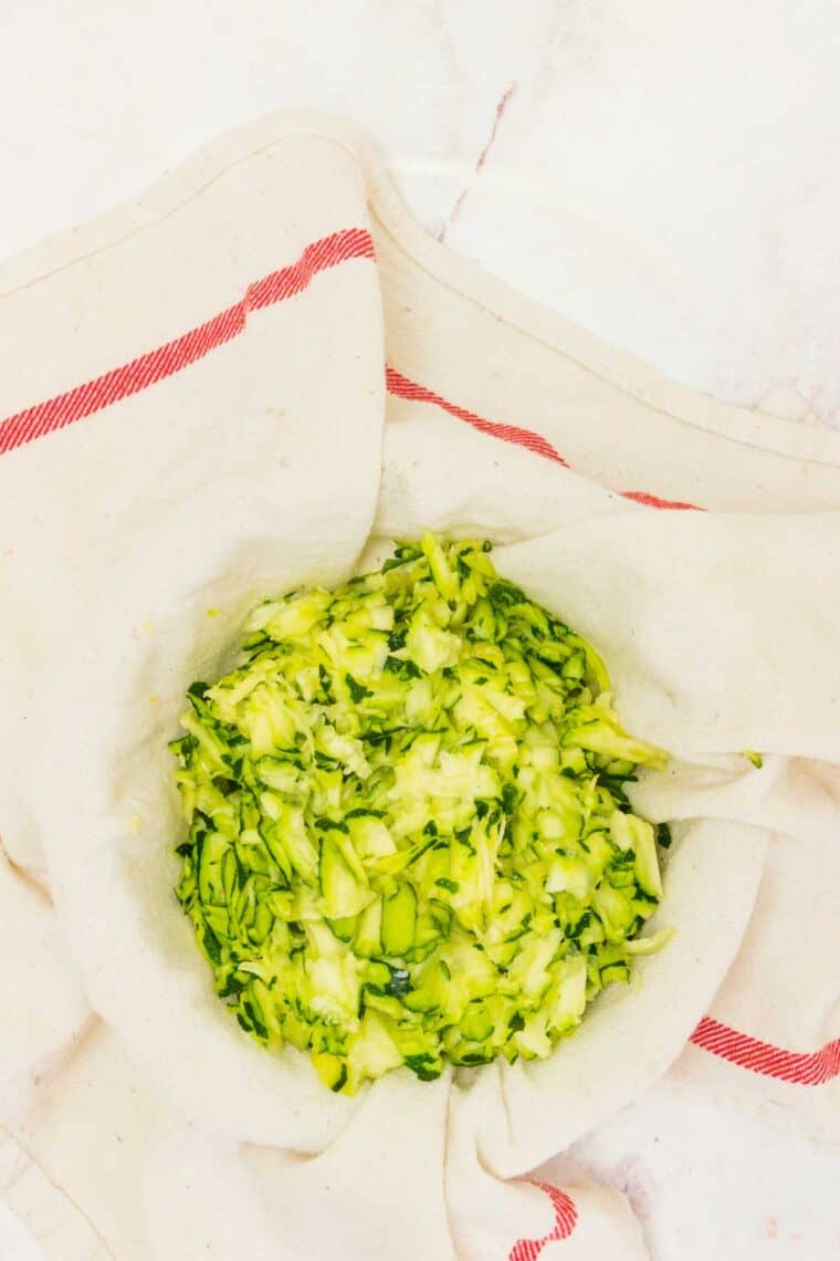 Shredded zucchini in a kitchen towel for draining.