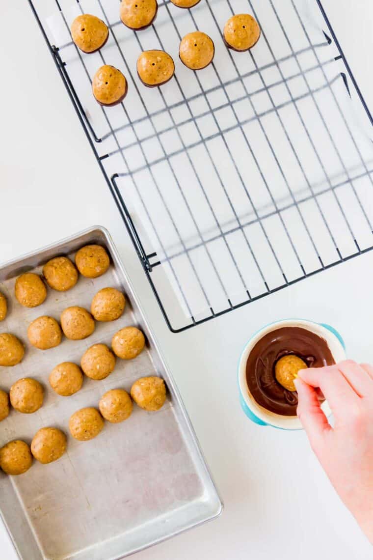 Dipping peanut butter balls in melted chocolate to make buckeyes.