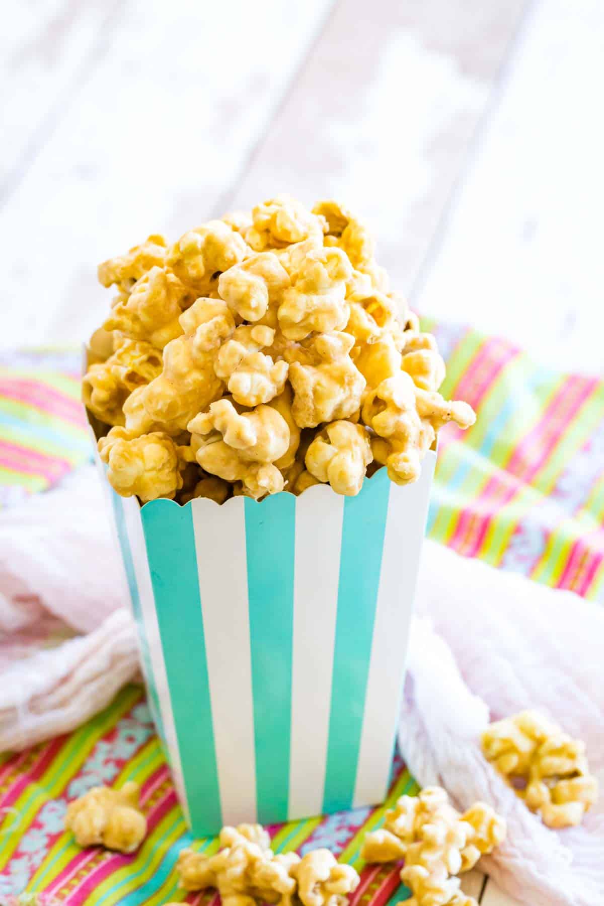 Peanut butter butterscotch popcorn is shown in a blue and white striped container.