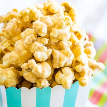 Peanut butter butterscotch popcorn is shown in a blue and white striped container.