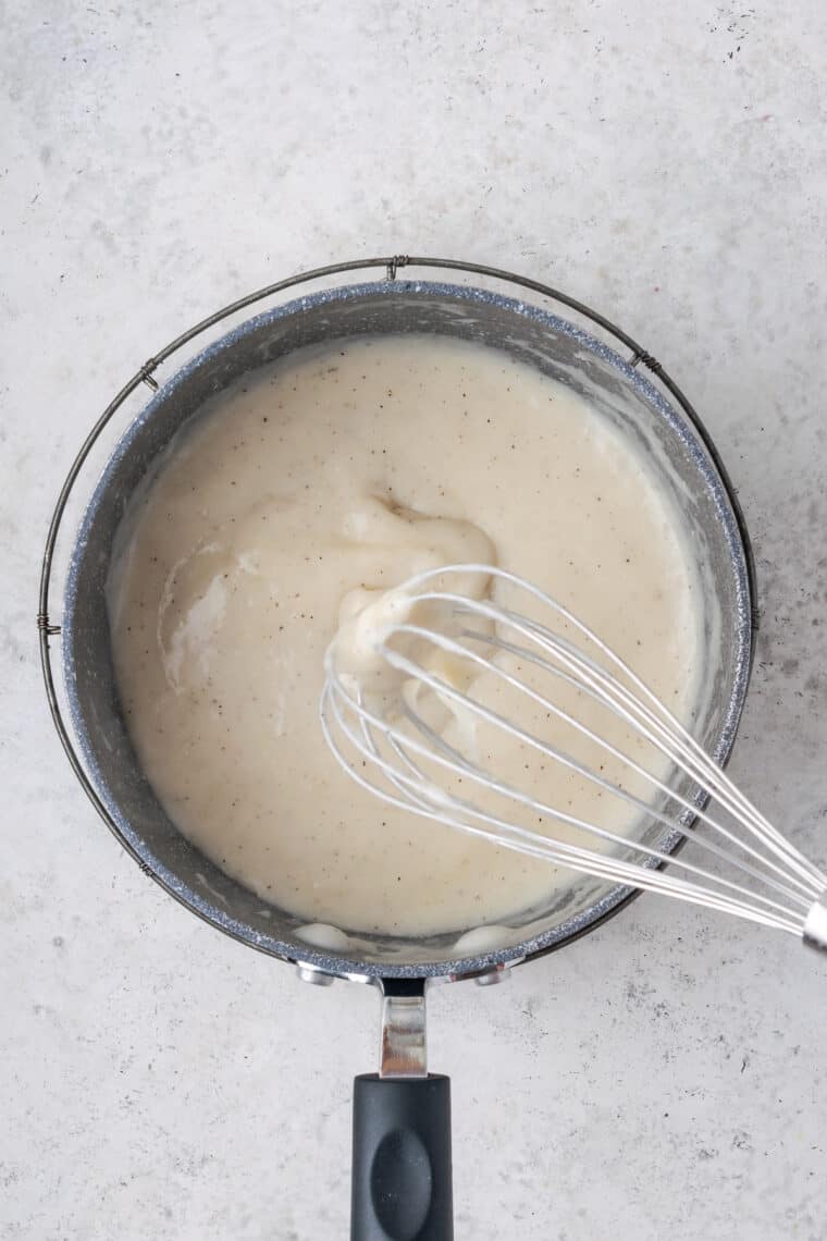 A whisk shows a thick cream soup.