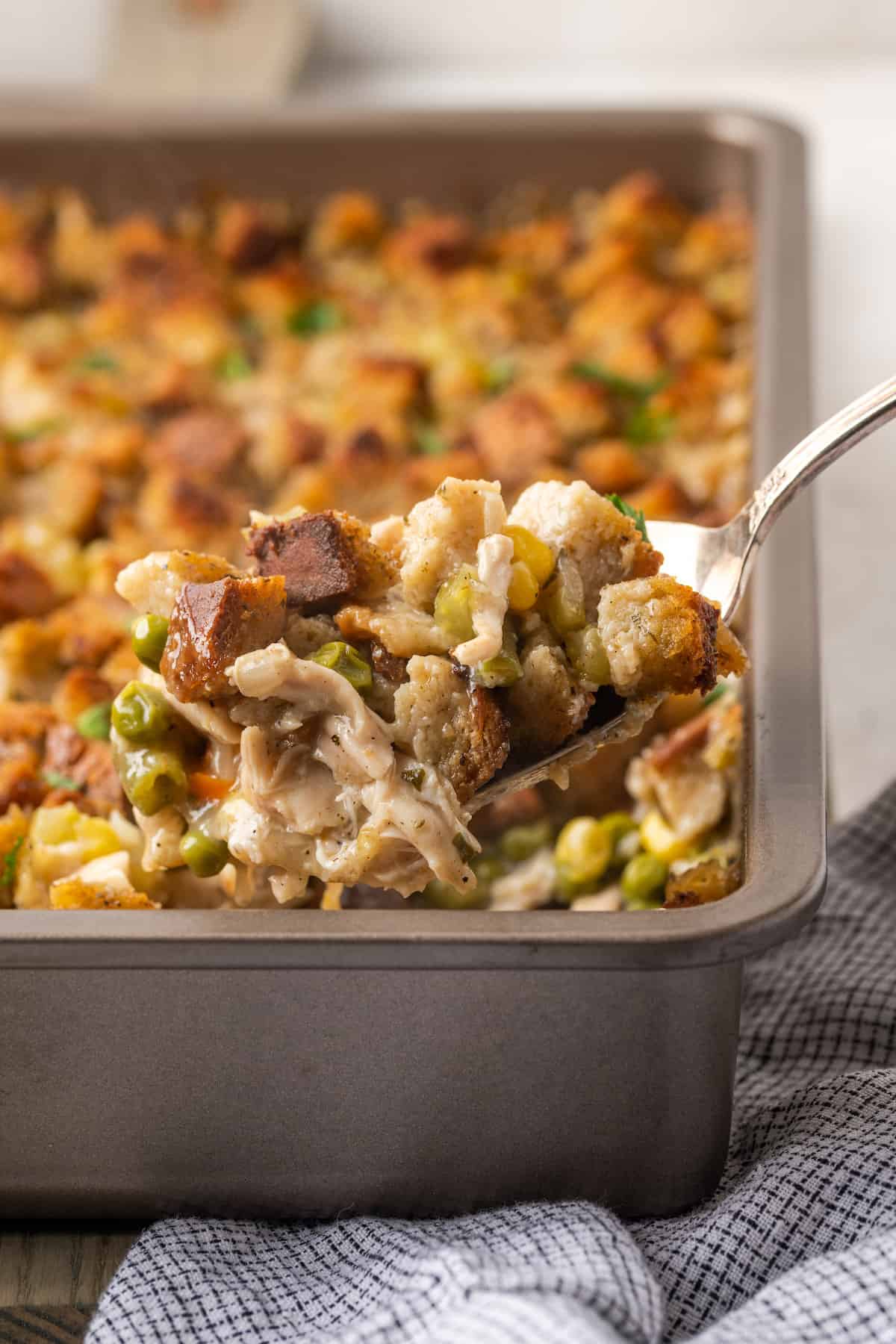 A spoon scoops out chicken and stuffing casserole.