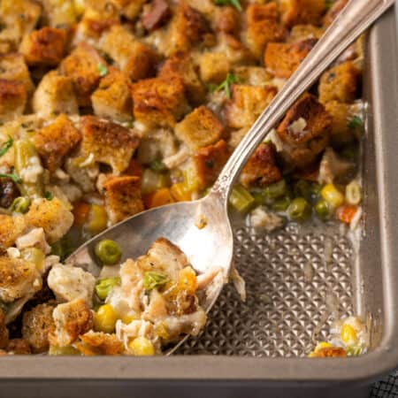 A spoon scoops out chicken and stuffing casserole.