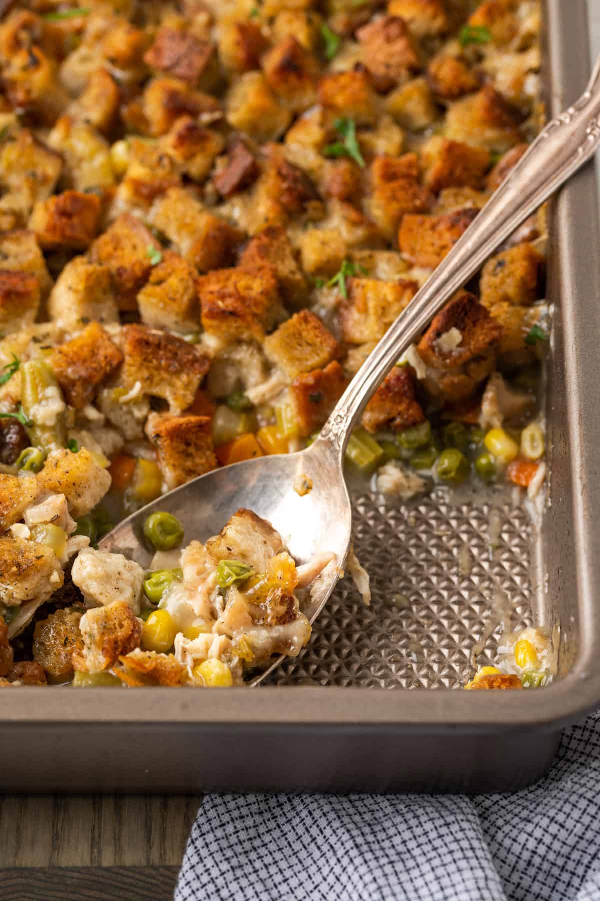 A spoon scoops out chicken and stuffing casserole.