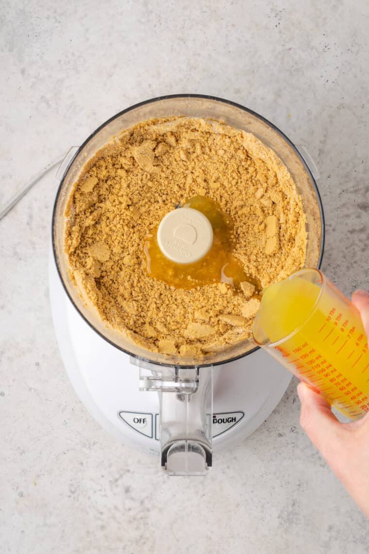 Pouring melted butter into a food processor.